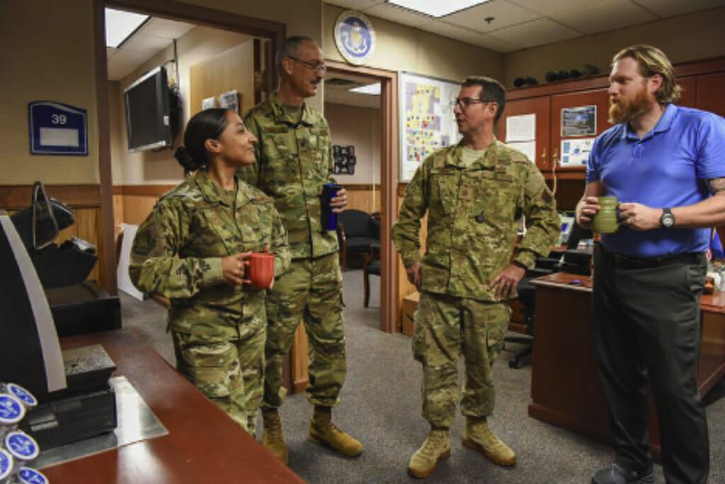 Four active-duty service members taking a moment to have a coffee with one another in an office setting.