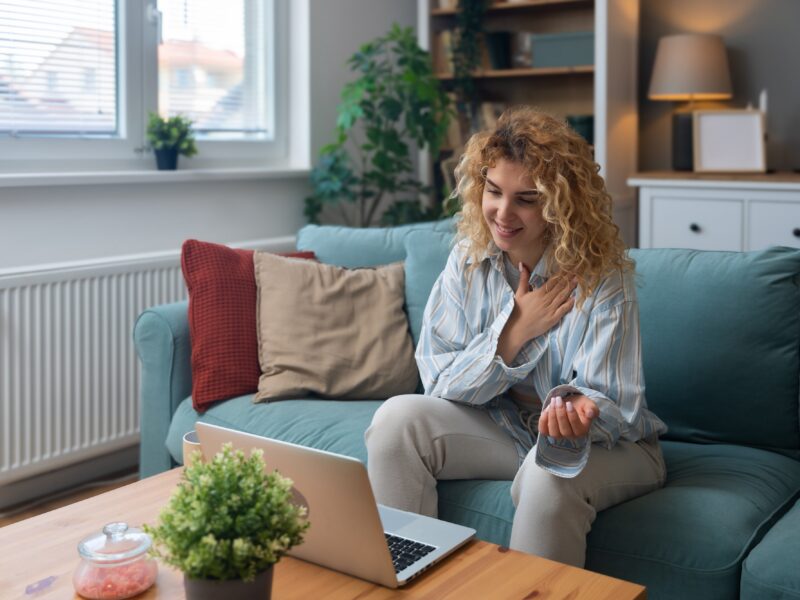 A woman sitting in her living room speaking to a telehealth therapist
