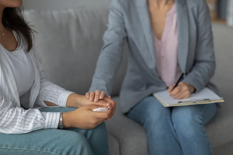 Therapist laying her hand on a patient’s hand in order to provide comfort.