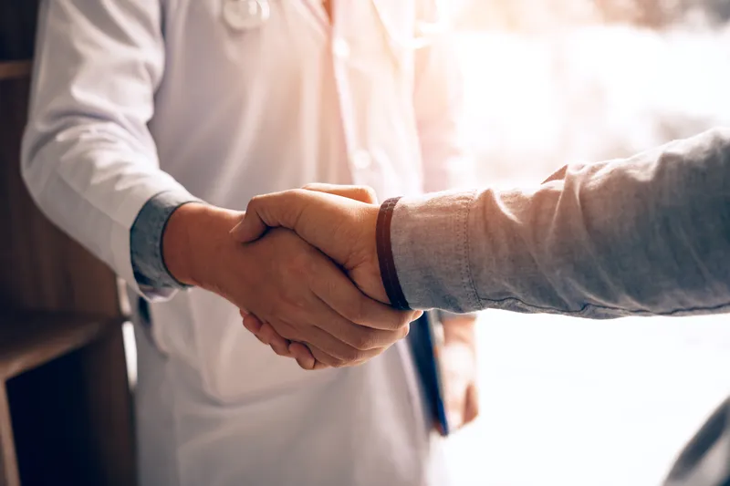 Doctor shaking hands with a patient in a clinic.